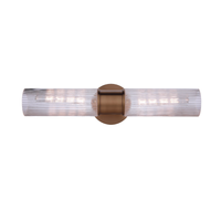 Modern vanity light with double-ended clear ribbed glass cylinders and a antique brass finish wall mount for modern bathroom lighting.