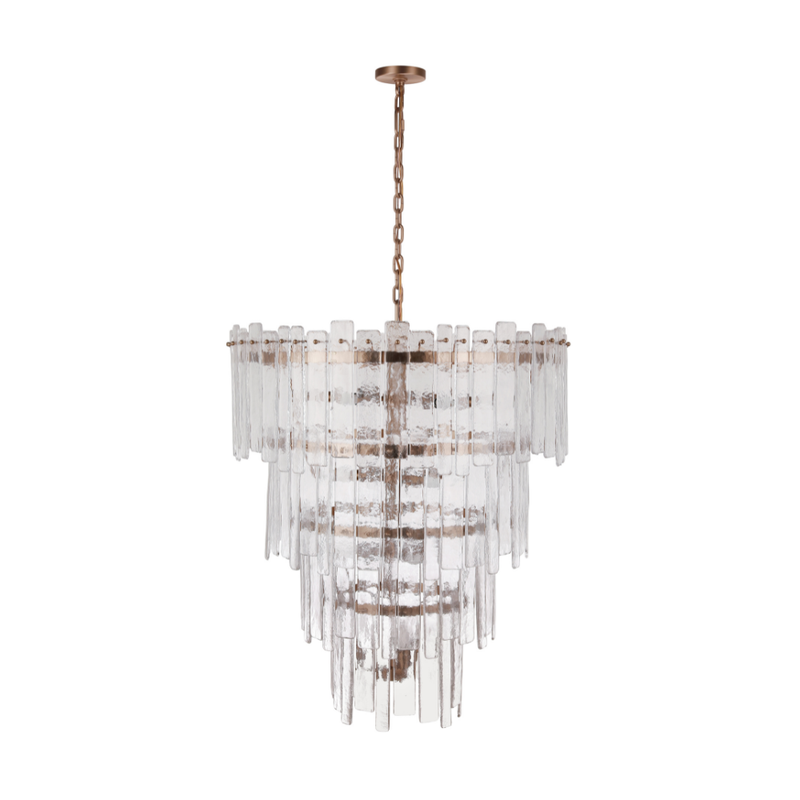 Tiered chandelier featuring textured clear ice glass panels suspended from an aged brass frame and chain