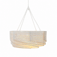 White woven rattan chandelier with layered drum shade and warm ambient lighting